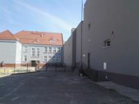 Zdjęcie przedstawia plac przed budynkiem przedszkola. W tle znajduje się budynek główny, po prawej stronie widoczna jest...